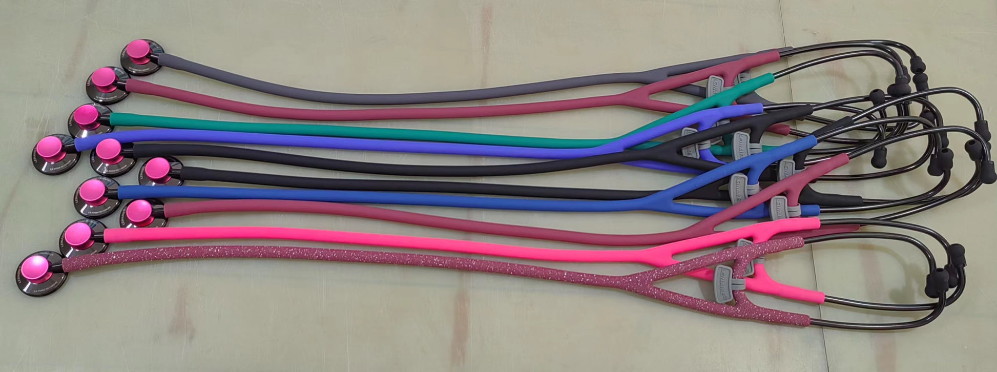 Set of colorful Leinaike pediatric stethoscopes on a beige surface