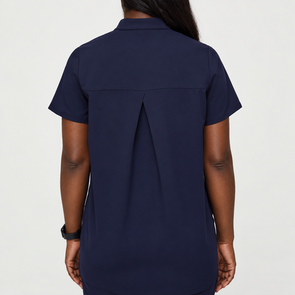 Back view of navy blue SMSG maternity scrub top showing box pleat detail for extra room and short sleeve relaxed fit
