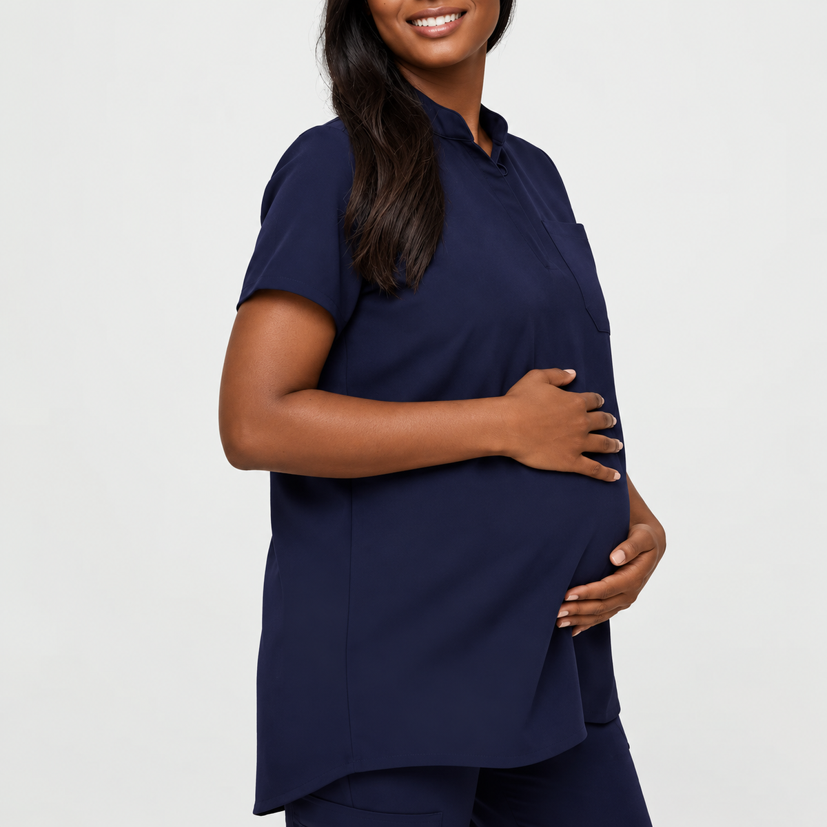 Navy blue SMSG maternity scrub top front side view on pregnant model showing mandarin collar hidden button and relaxed A-line fit