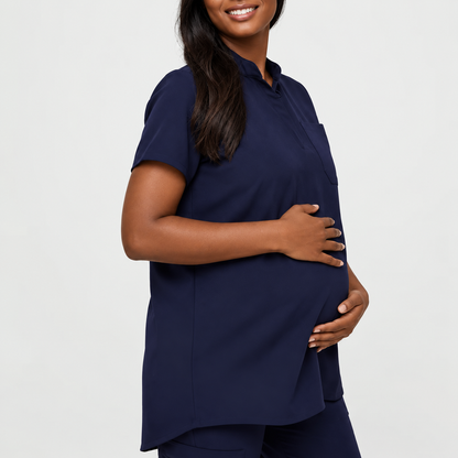 Navy blue SMSG maternity scrub top front side view on pregnant model showing mandarin collar hidden button and relaxed A-line fit