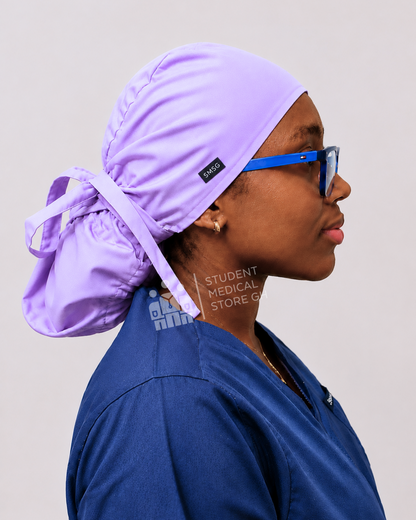 Female doctor wearing grey scrubs  and glasses with a side view of SMSG lilac scrub cap.
